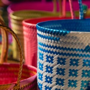 Brightly colored handwoven baskets with intricate patterns illuminated by sunlight, showcasing craftsmanship.