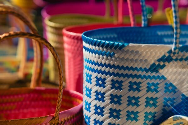 Brightly colored handwoven baskets with intricate patterns illuminated by sunlight, showcasing craftsmanship.